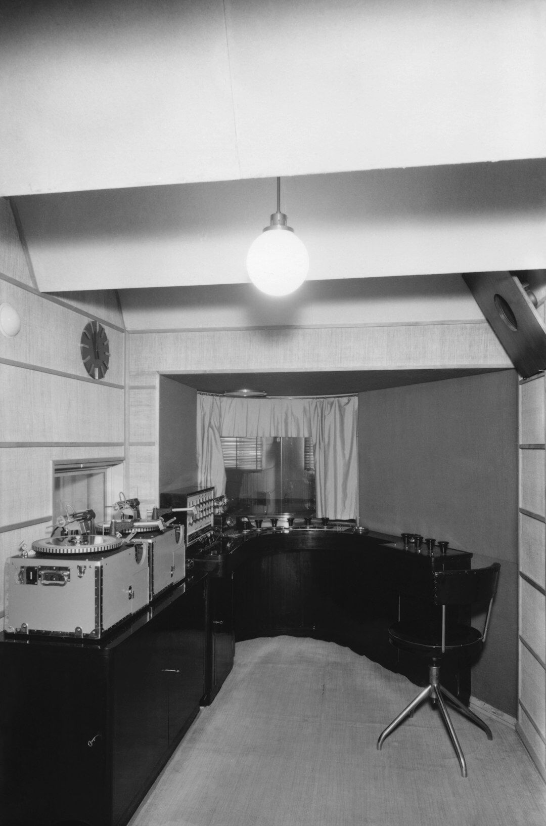 Presenter sitting in a retro television studio under warm stage lights